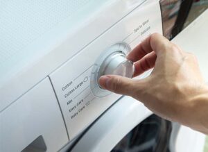 person turning the dial on a washing machine