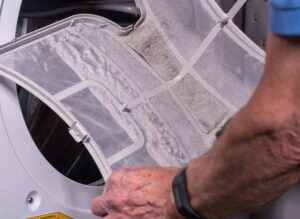 man cleaning out lint trap in dryer